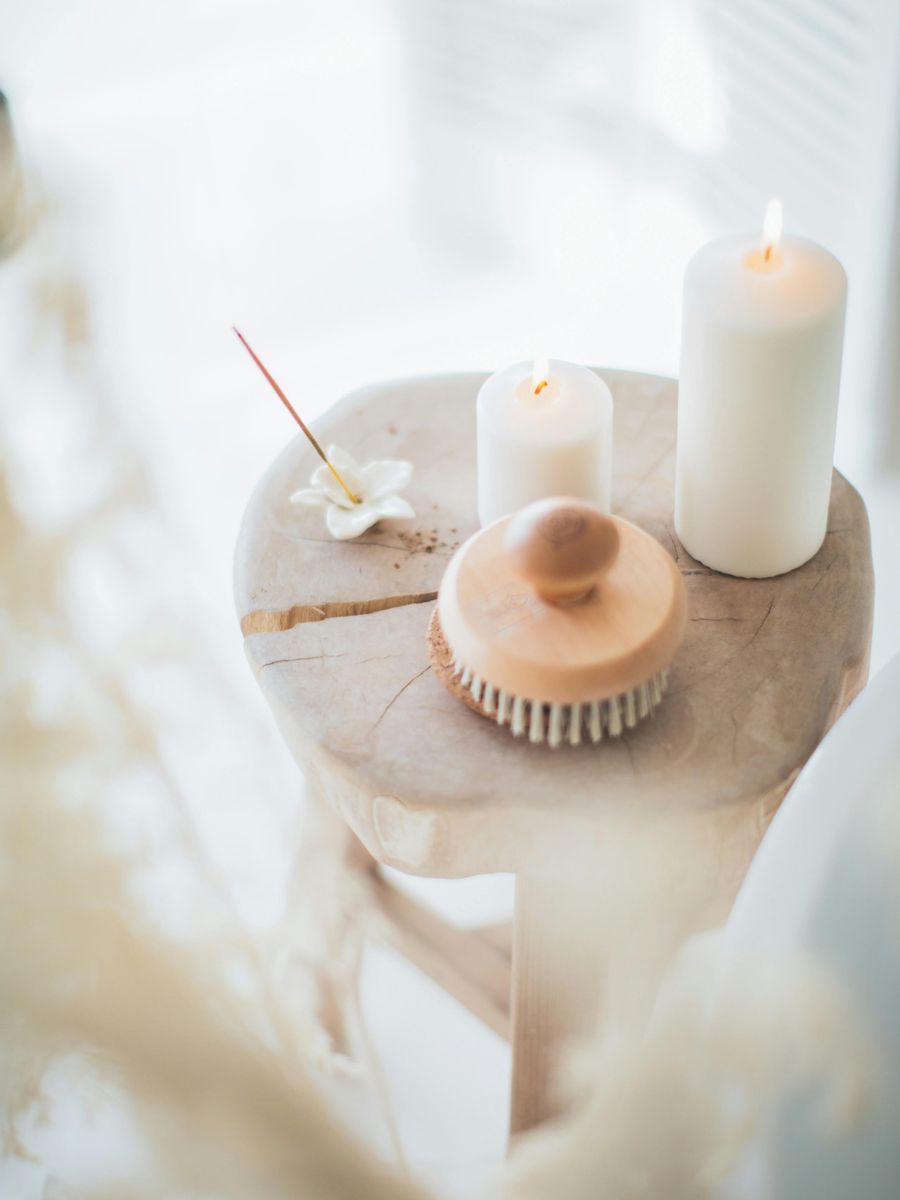 Lit candles and a wooden body brush resting on a stool